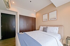 Un dormitorio con una cama, un armario y dos cuadros en la pared.