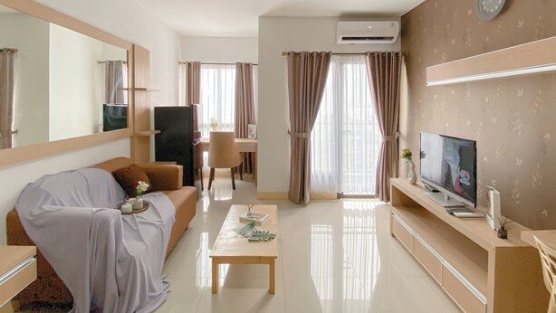 A modern living room with a sofa, a coffee table, a TV, and a large mirror. - Scandinavian Minimalist 2Br At Tamansari Semanggi Apartment (Jakarta)