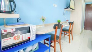 Une cuisine compacte équipée d’un four à micro-ondes, d’une bouilloire et d’un petit coin repas avec des chaises et une table.