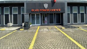 Das Gebäude des Elvis Fitness Centers mit schwarzem Mauerwerk, großen Fenstern und einem roten Markisenvorbau.