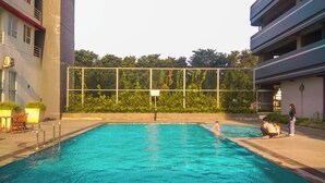Ein Schwimmbecken mit Metallzaun, einem Stuhl und einem Tisch auf der linken Seite.