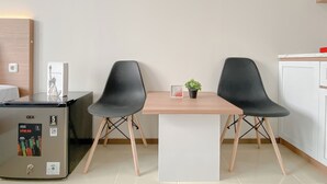 Quarto moderno com uma mesa de madeira, duas cadeiras pretas, uma pequena planta em vaso e uma geladeira GEA.