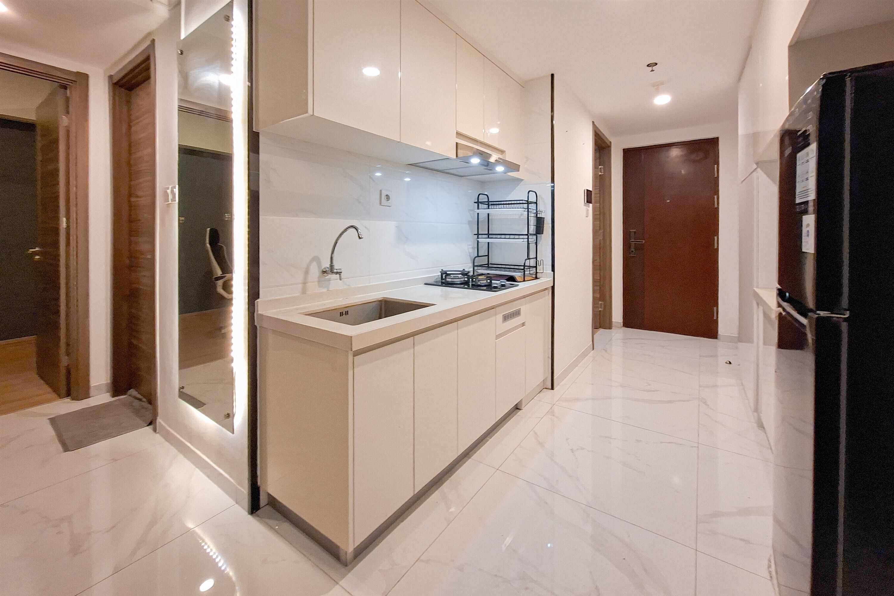 A modern kitchen with a built-in sink, a stove, and a black refrigerator.