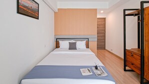 Quarto de hotel bem arrumado, com uma cama, um guarda-roupa de madeira e um quadro na parede.
