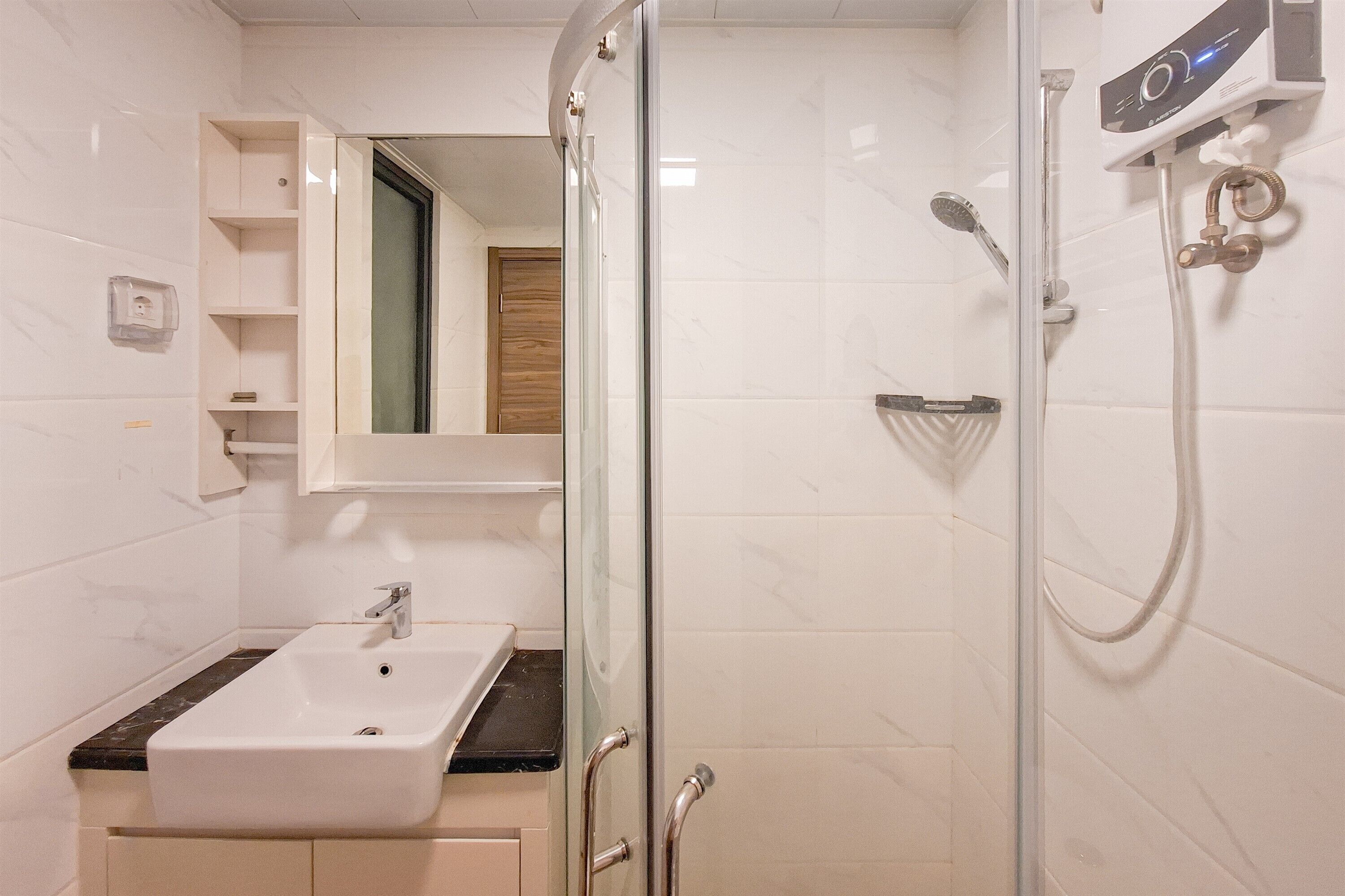 Un baño con ducha envuelta en vidrio, un lavabo blanco y un espejo sobre él.
