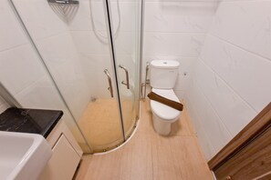 A bathroom with a glass shower enclosure, a white toilet, and a bathtub. - Monochromatic 2Br With Extra Working Room Apartment Sky House Bsd (Pagedangan)