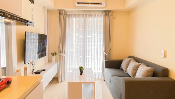 Ein modernes Wohnzimmer mit Flachbildfernseher, einer Couch, einem Couchtisch und einem großen Fenster mit Vorhängen.