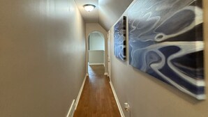 A hallway with a wooden floor, white walls, and a ceiling light. - Cozy 5BR / 2.5BA- Brick Home in Olive Branch (Olive Branch)