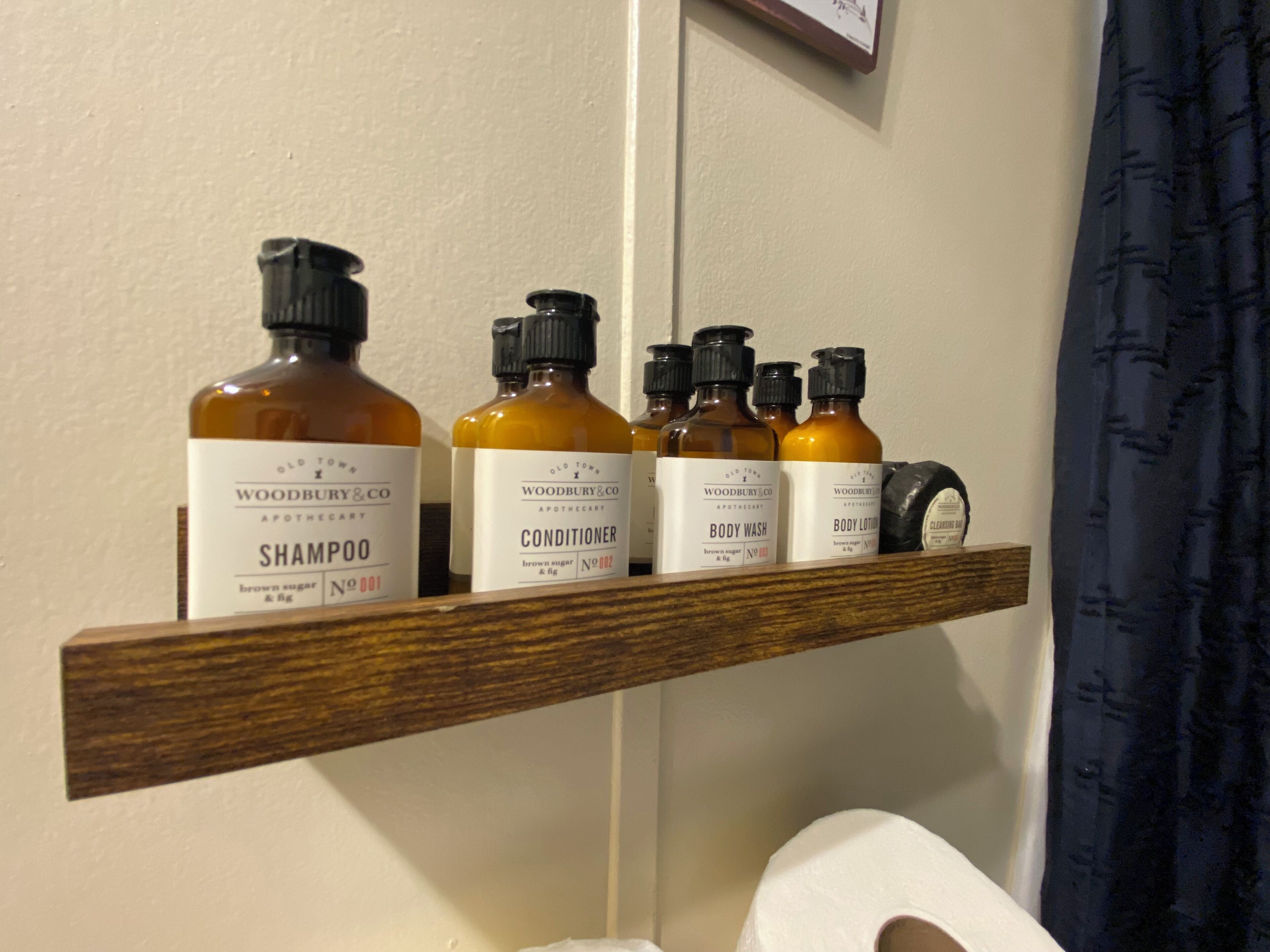 Een plank met flesjes toiletartikelen, zoals shampoo, conditioner, douchegel en bodylotion.