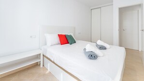 Un dormitorio moderno con cama, mesita de noche, banco y armario.