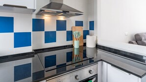 Una cocina moderna con encimera negra, estufa de acero inoxidable y salpicadero de azulejos azules y blancos.