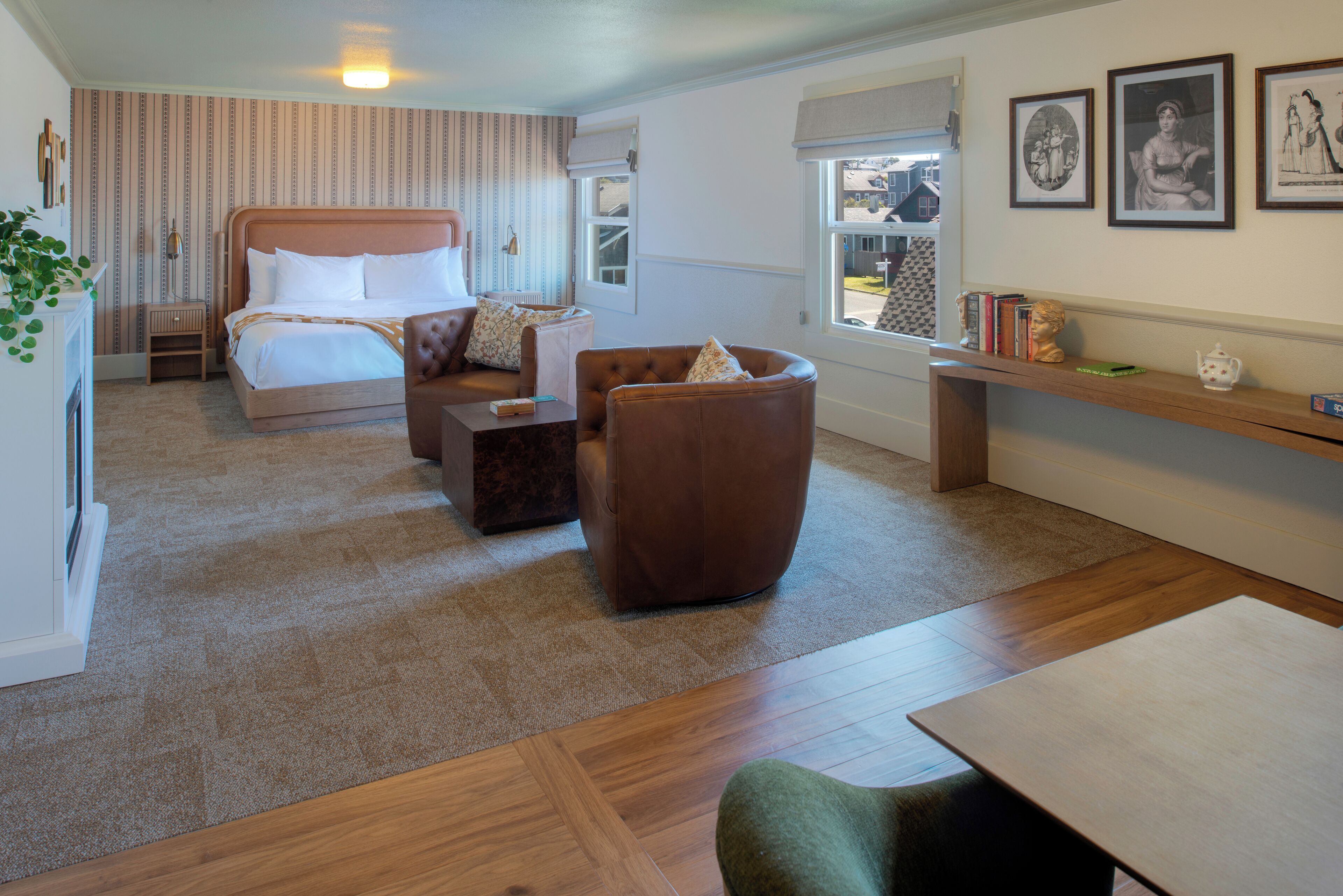 A hotel room with a bed, a seating area with a sofa and armchair, a small table, and a window with a view of the outside.