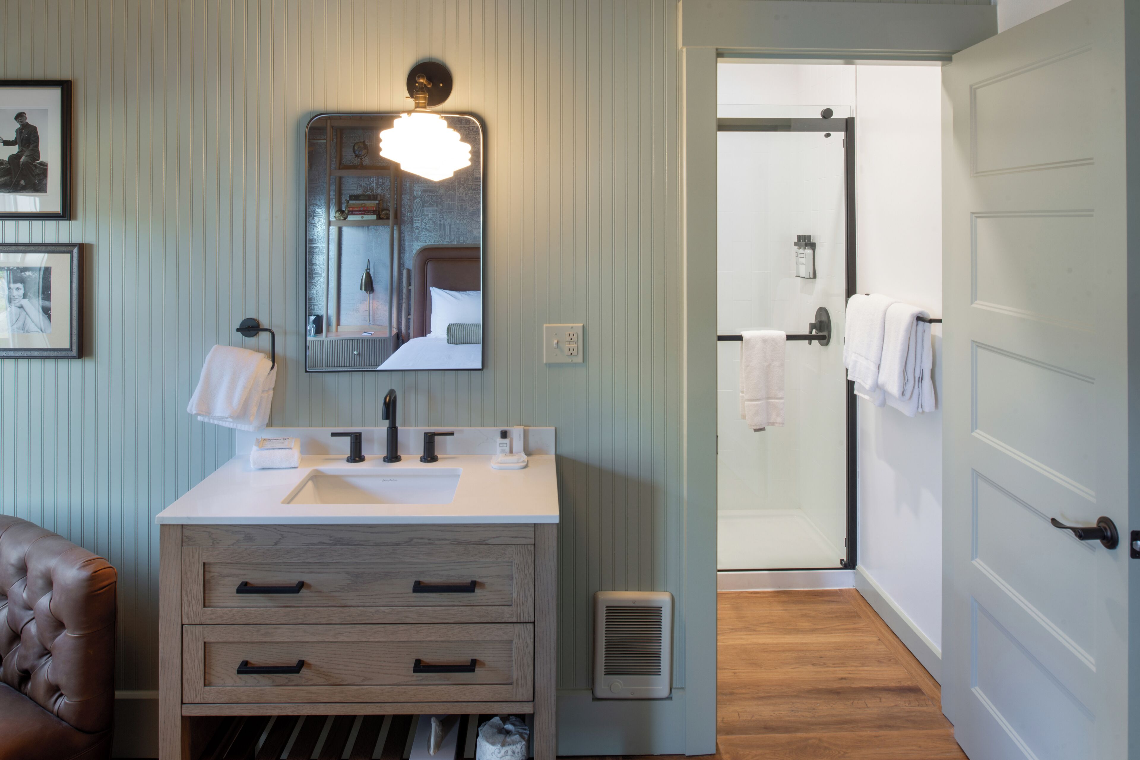 A bathroom with a wooden vanity, a large mirror, and a shower area.