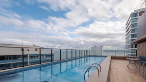 A rooftop swimming pool with a clear view of the sky and clouds, surrounded by modern buildings. - 1 Bedroom Apart w/ Air 120m From the Beach Esb0310 (Salvador)
