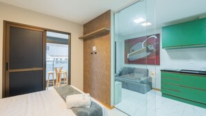 A modern hotel room with a bed, a small seating area with chairs, a glass partition separating the room from a kitchenette with green cabinets. - 1 Bedroom Apart w/ Air 120m From the Beach Esb0310 (Salvador)