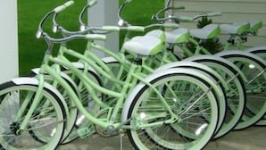 Varias bicicletas estáticas con estructura verde y asientos blancos, estacionadas al aire libre.