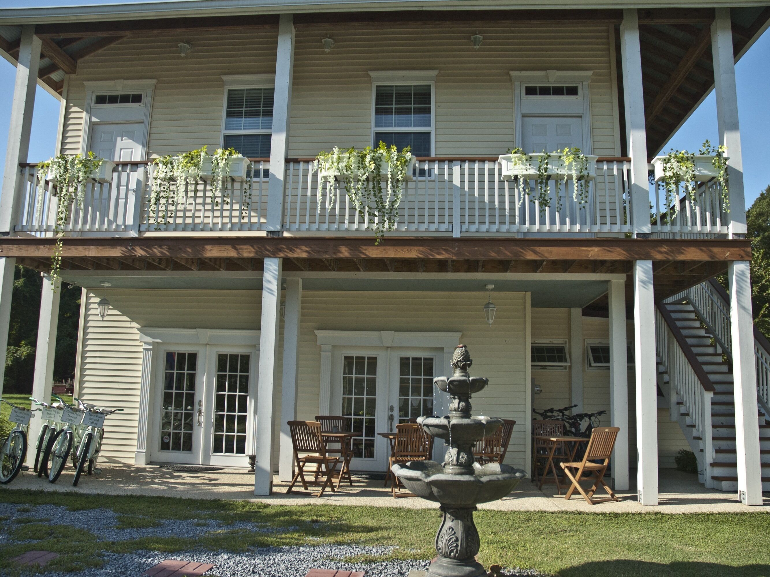 A two-story building with a covered porch, a fountain, and outdoor seating.