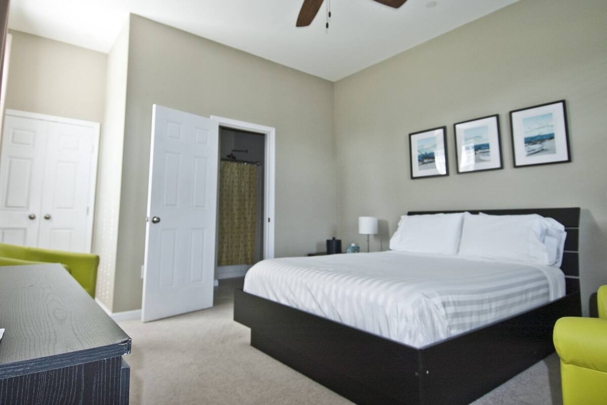 A bedroom with a bed, a ceiling fan, a door, and a chair.