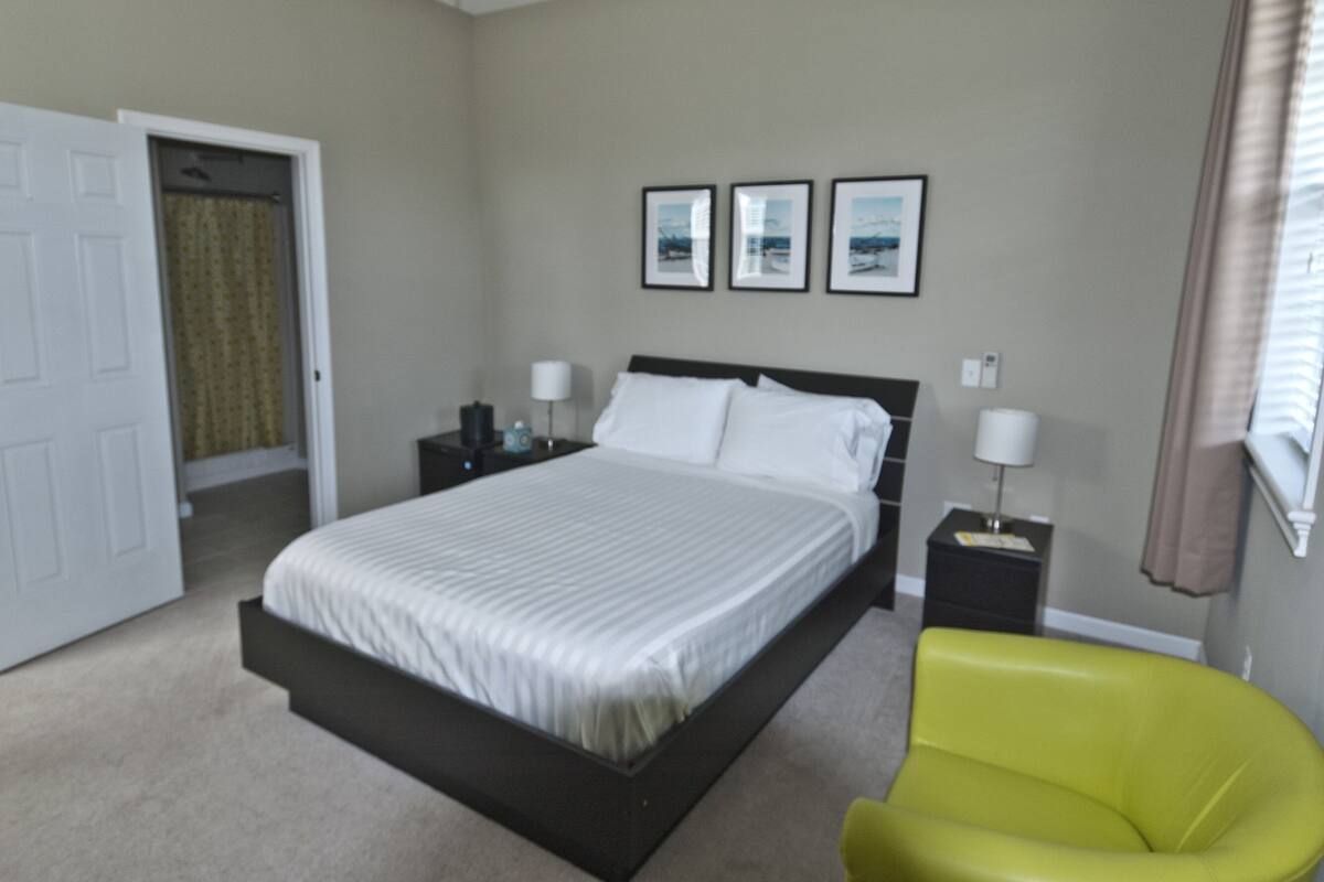 A bedroom with a bed, nightstands, a chair, and a door.