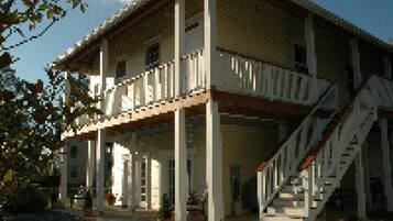 A two-story building with a balcony on the upper floor, a staircase leading to the entrance, and a covered porch area.