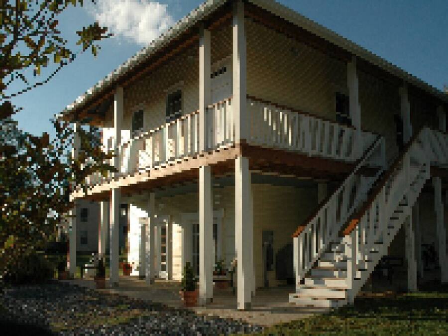A two-story building with a balcony on the upper floor, a staircase leading to the entrance, and a covered porch area.