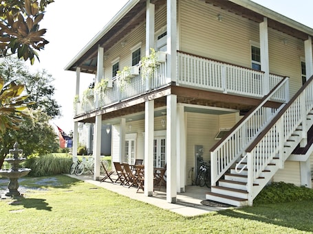 A two-story house with a covered porch, a staircase, and a garden area.