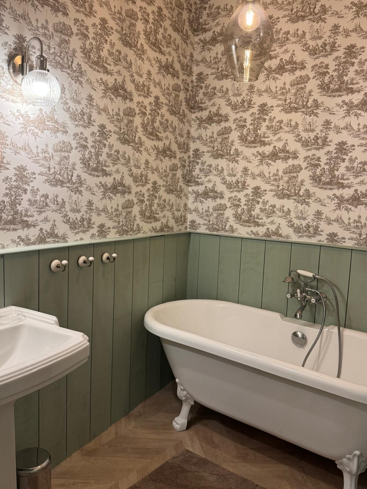 A bathroom with a freestanding bathtub, a sink, and a wall-mounted light fixture.
