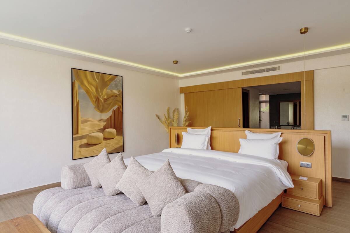 Een moderne slaapkamer met een groot bed, een houten hoofdbord en een groot kunstwerk in een lijst aan de muur.