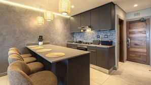 Cocina moderna con una isla central, armarios oscuros e iluminación colgante.