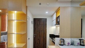 A modern kitchen with built-in shelves, a wooden door, and a countertop with three kettles.