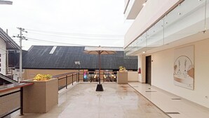 An indoor corridor with a tiled floor, a glass railing, and a ceiling with skylights.
