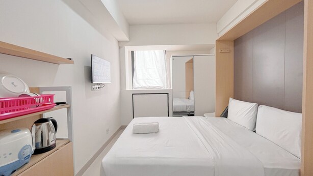 Ein Hotelzimmer mit Bett, Fernseher, Fenster und Spiegel.