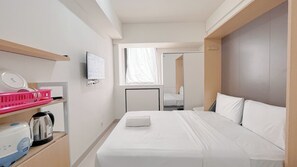 A hotel room with a bed, a TV, a window, and a mirror. - Great Deal Studio (No Kitchen) At Bandaraya - Tallasa City Makassar Apartment (Makassar)