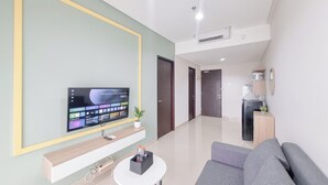 A modern living room with a flat-screen TV, a small table, and a gray sofa. - Simply Look 1Br Apartment Patraland Amarta (Ngaglik)