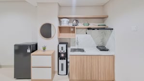 Una cocina compacta equipada con refrigerador, dispensador de agua, lavamanos y microondas.