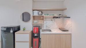 Eine kleine Küche mit Kühlschrank, Kaffeemaschine, Mikrowelle, Spüle und Herd.