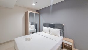 Ein modernes Hotelzimmer mit einem großen Bett, einem Nachttisch, einem Spiegel und einem Kleiderschrank.