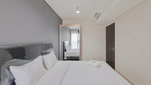 A hotel room with a large bed, a wooden headboard, a mirror, and a door.