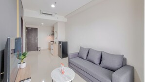 A modern living room with a grey sofa, a small round coffee table, and a TV on a wooden stand.