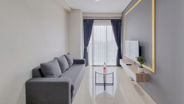 A modern living room with a sofa, a glass coffee table, a TV, and a large mirror.