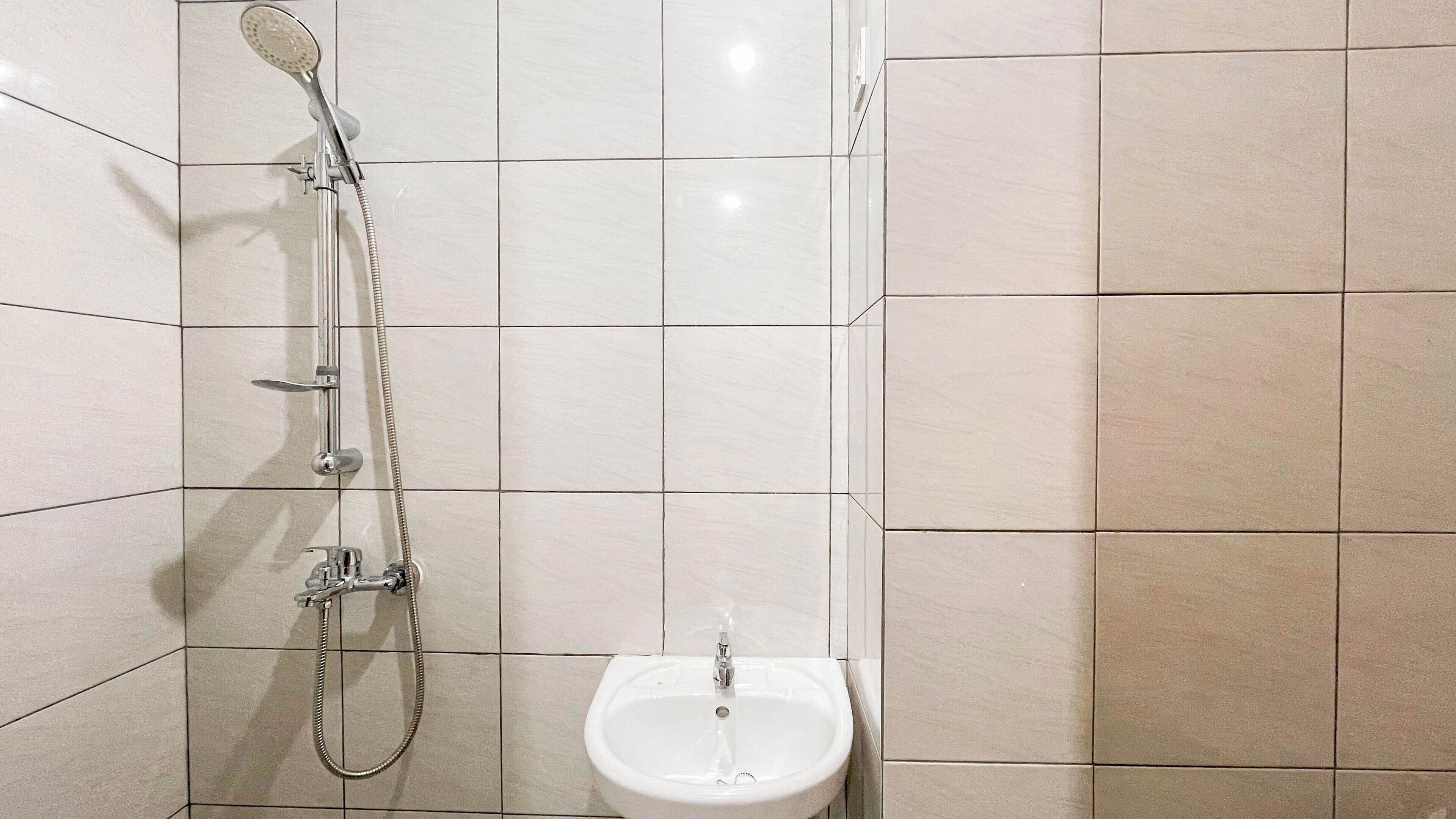 A bathroom with a shower, a sink, and tiled walls.