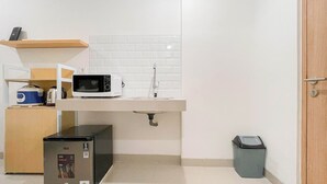 A compact kitchenette with a microwave, sink, and small refrigerator. - Standard Studio (No Kitchen) At Bandaraya - Tallasa City Makassar Apartment (Makassar)