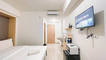 Habitación de hotel con una cama, un televisor mostrando 'Avengers', un microondas, un lavabo y una puerta que conduce a otra habitación.