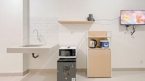 A compact kitchen with a sink, microwave, and small refrigerator. - Studio (No Kitchen) Apartment At Bandaraya - Tallasa City Makassar Near Unhas (Makassar)