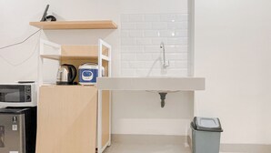 A compact kitchen with a microwave, toaster, and cabinets, a sink with a faucet, and a trash bin. - Compact Studio (No Kitchen) At Bandaraya - Tallasa City Makassar Apartment (Makassar)