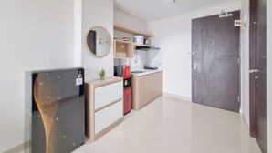 A compact kitchen with a refrigerator, a coffee machine, and a microwave. - Spacious Apartment 1Br At Patraland Amarta (Ngaglik)