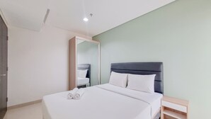 A modern hotel room with a large bed, a bedside table, a wardrobe, and a mirror. - Spacious Apartment 1Br At Patraland Amarta (Ngaglik)