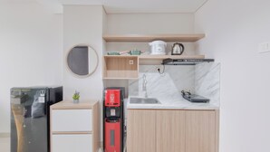 A compact kitchen with a refrigerator, coffee maker, and a microwave. - Spacious Apartment 1Br At Patraland Amarta (Ngaglik)