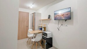 Ein kompakter Wohnbereich mit Küchenzeile, Essbereich und einem an der Wand befestigten Fernseher.