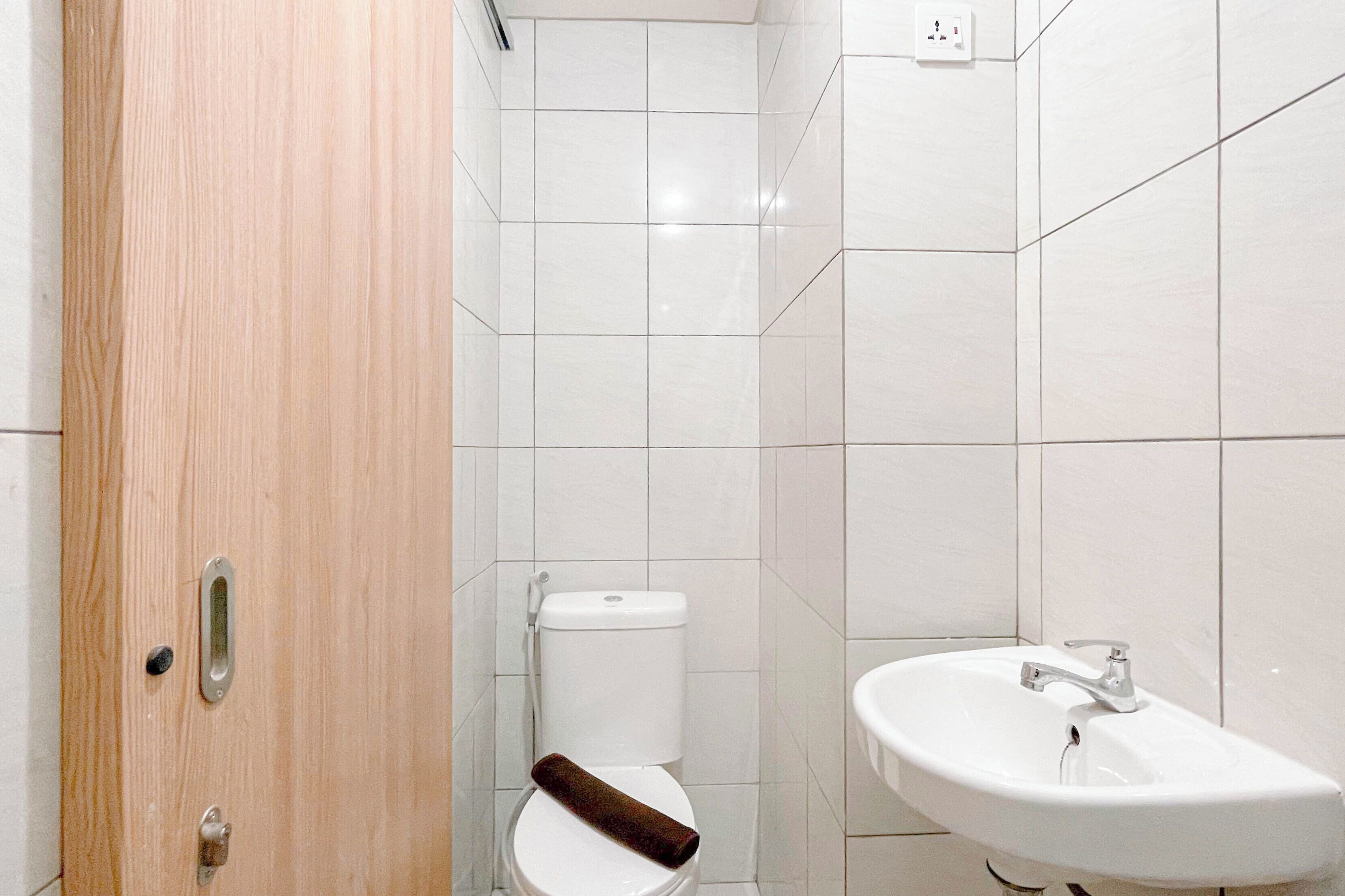 A bathroom with a wooden door, a white toilet, and a white sink.